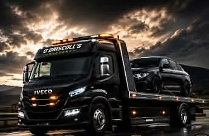 Recovery truck with a loaded car driving on a wet motorway under a dramatic sky